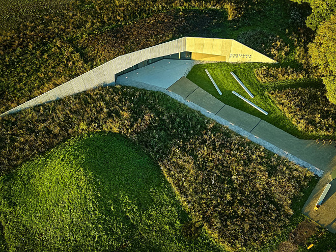 Der moderne, in der Erde verschwindende Bau des Heidengrabenzentrums aus der Luft, umringt von Wiese und Grünfläche.