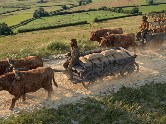 Eine Illustration zweier keltischer Lastwagen von Ochsen gezogen auf einem Feldweg im Hintergrund, Wiesen und Hecken.