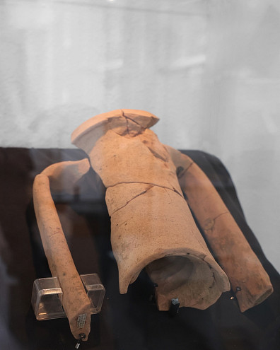 Keramikscherben hinter einer Vitrine auf schwarzem Hintergrund.
