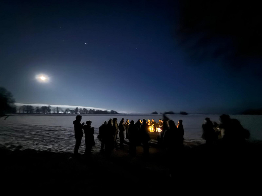 Eine Besuchergruppe versammelt sich bei einer nächtlichen Führung am Heidengraben um ein kleines Feuer. Über der winterlichen Landschaft leuchtet der Vollmond und macht den historischen Ort auch heute zu einem Treffpunkt für gemeinsame Erlebnisse.